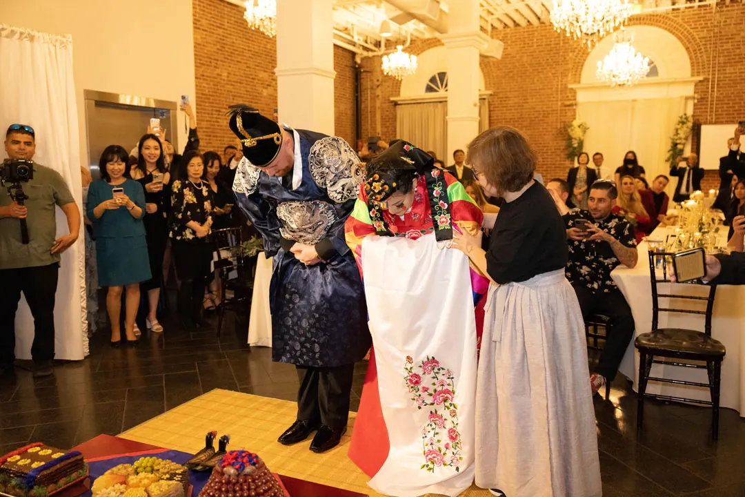 Wedding guests gather around a couple on the ballroom floor.
