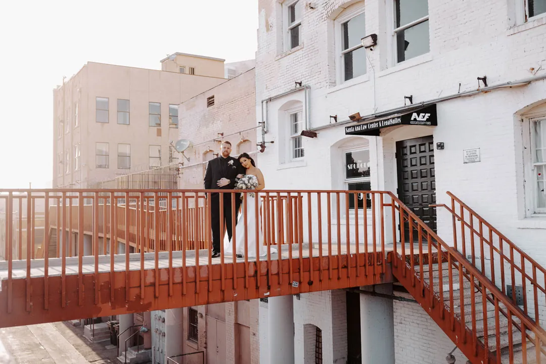 Couple embrace on a red outdoor stairway.