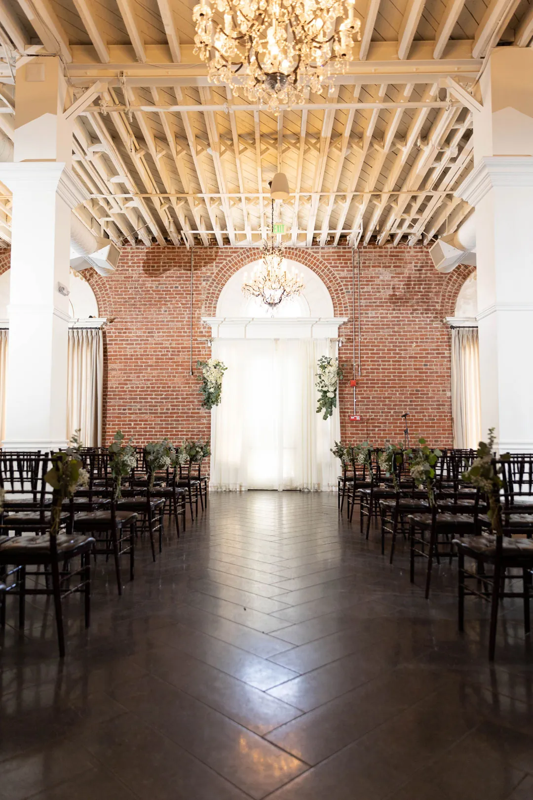 Empty ceremony aisle beneath crystal chandeliers.