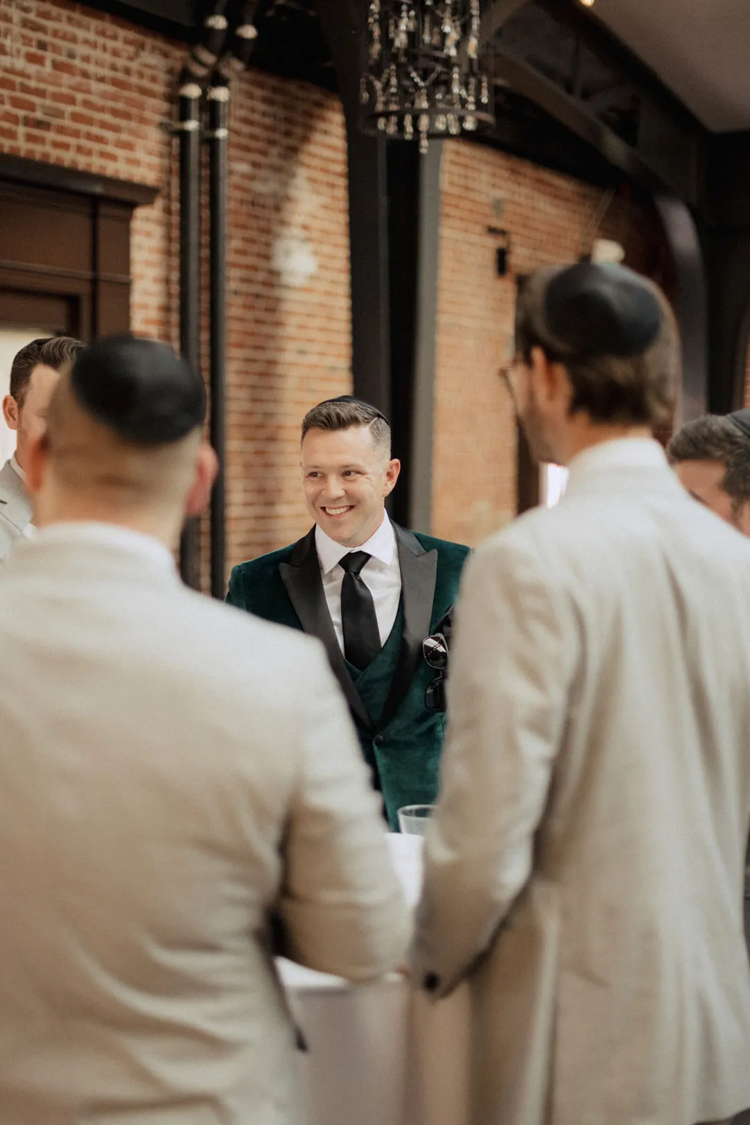 Groom smiling as attendants gather around him