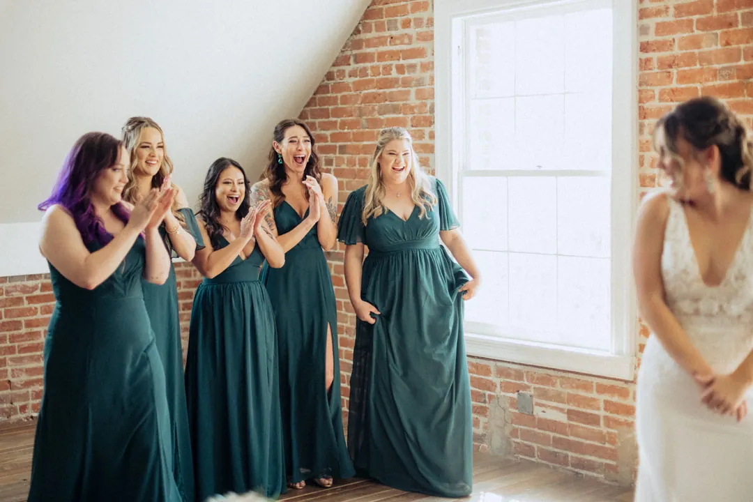 Bride and bridesmaids laughing in a sunlit room
