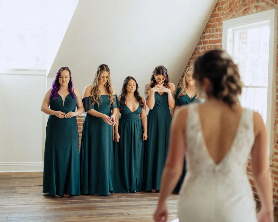 Bridesmaids reacting as they see the bride's dress