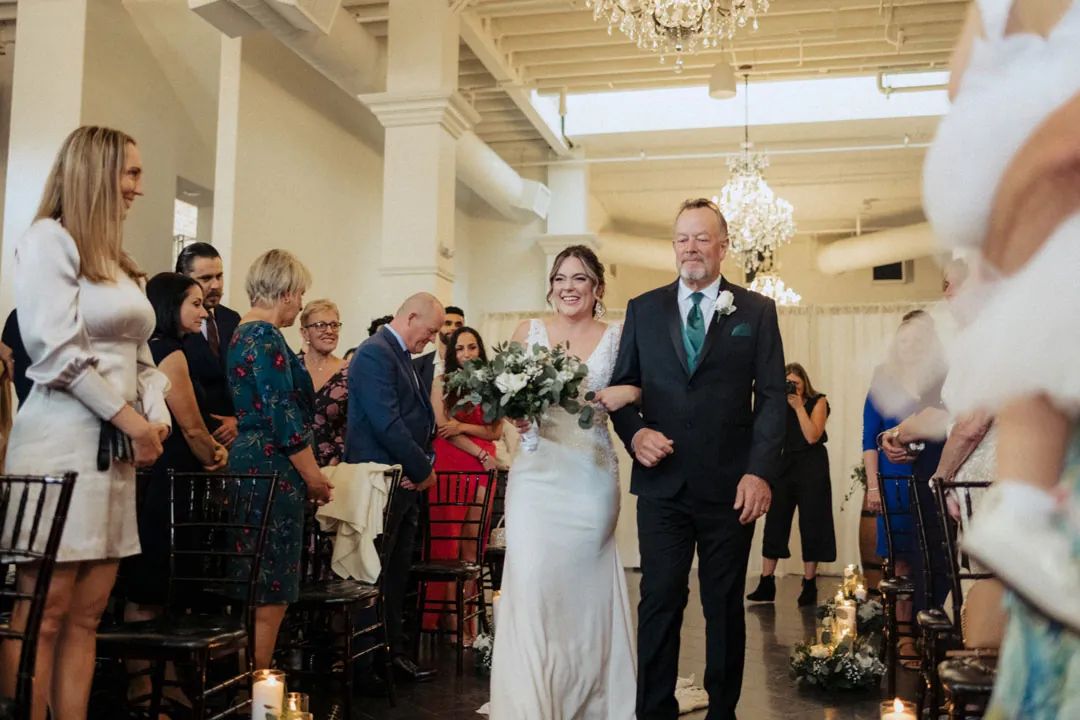 Guests smiling as attendants walk down the ceremony aisle