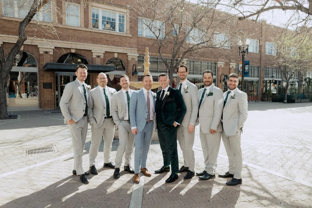 Groom and groomsmen posing on a sunlit city street