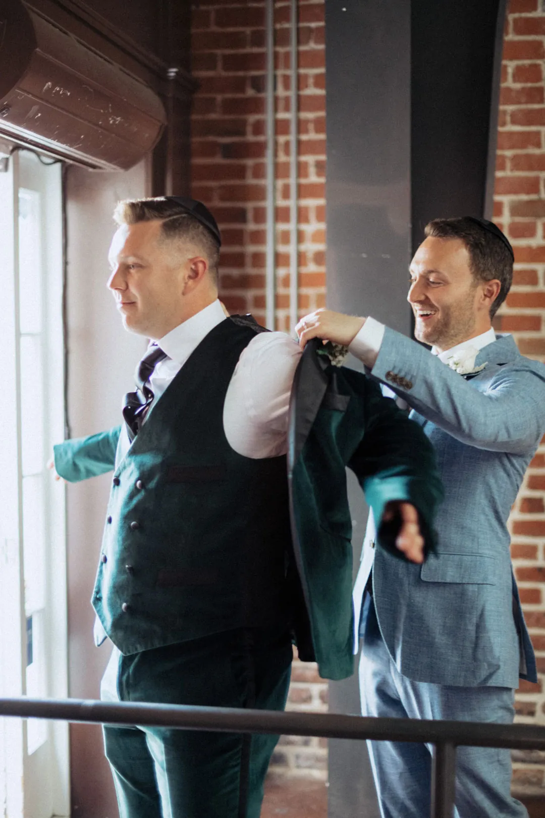 Attendant helping the groom into his suit jacket