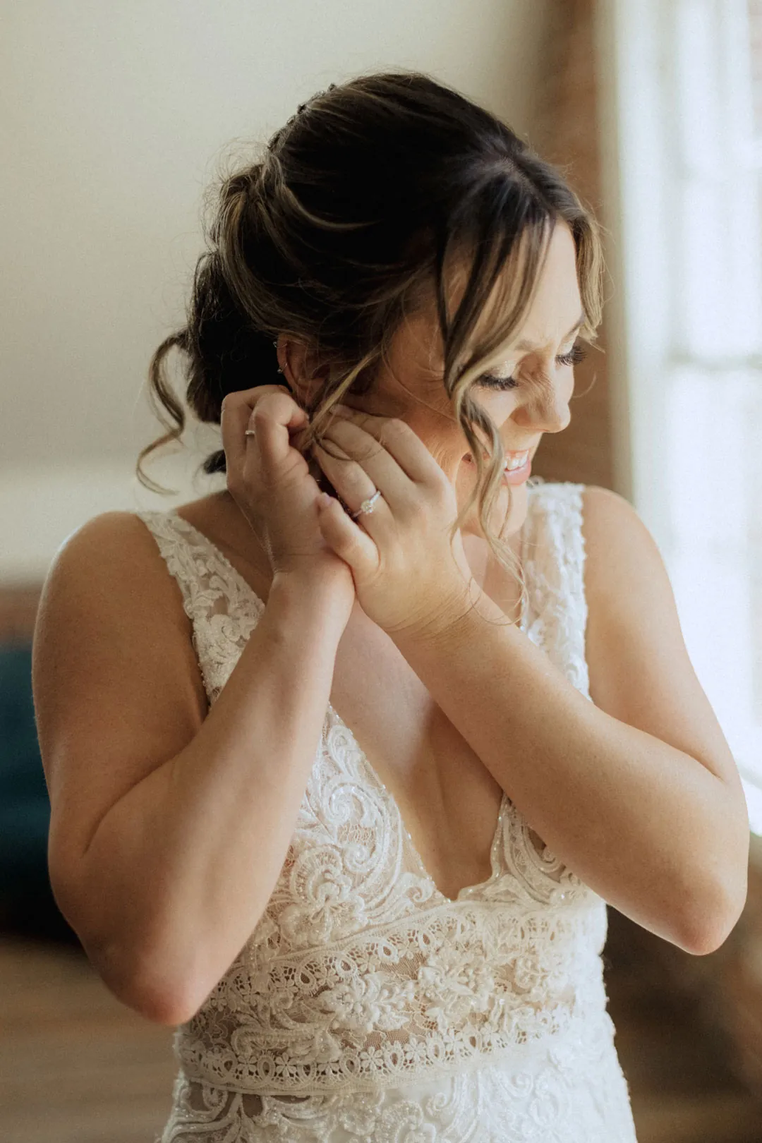 Bride fastening an earring near a window