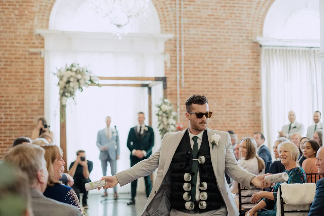 Attendant walking down the ceremony aisle with arms outstretched