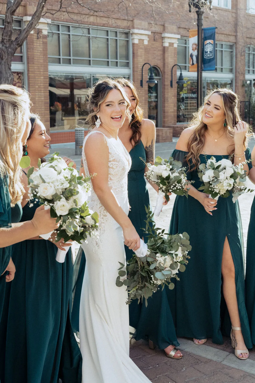 Bride and bridesmaids smiling while holding bouquets outdoors
