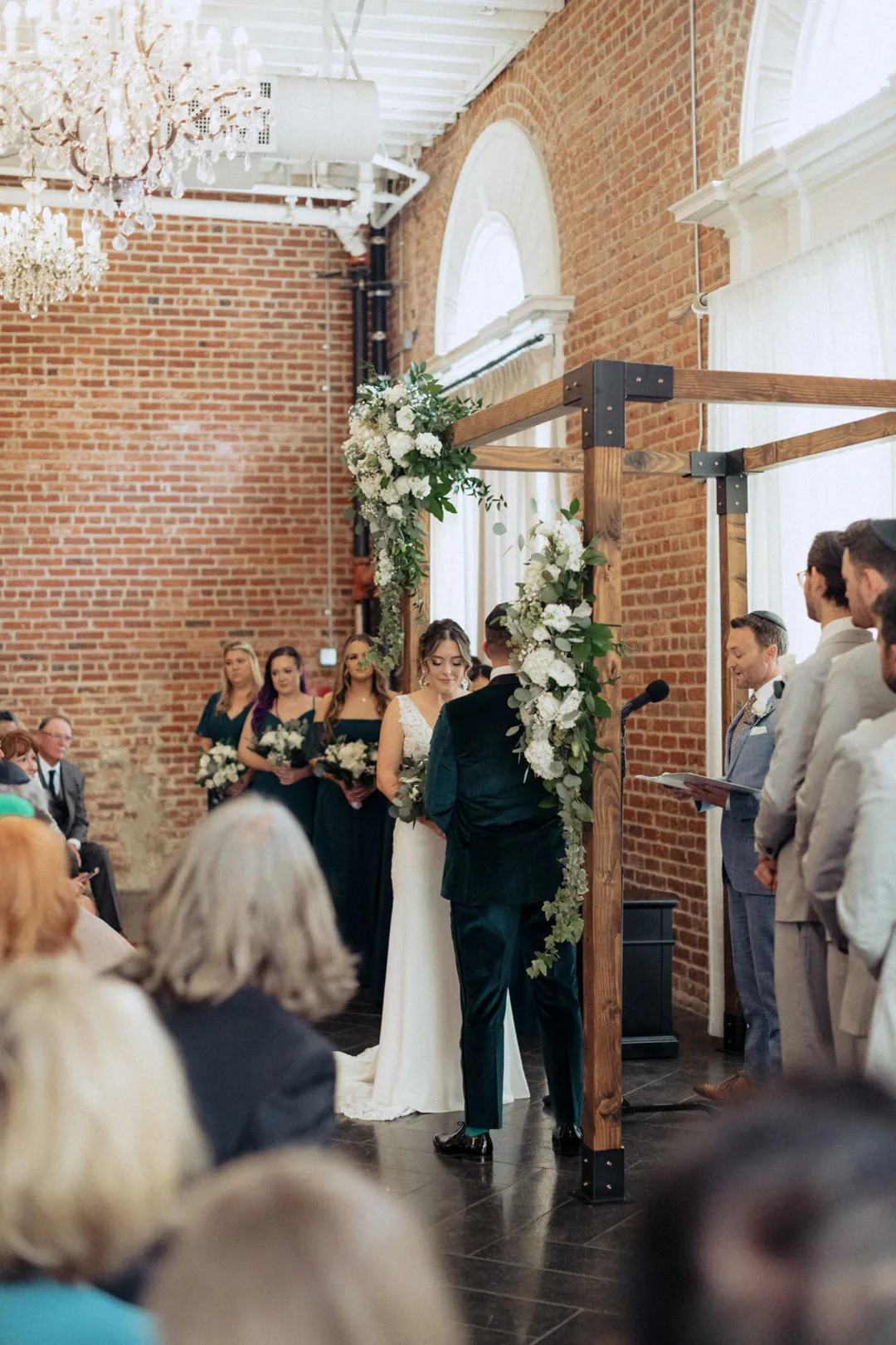 Wedding party standing beside a floral ceremony arch