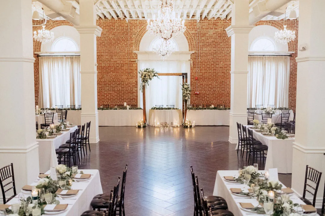 Reception tables framing a center aisle beneath chandeliers