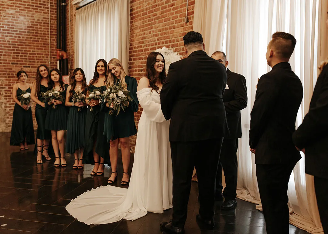 Couple stand together before a draped ceremony backdrop.