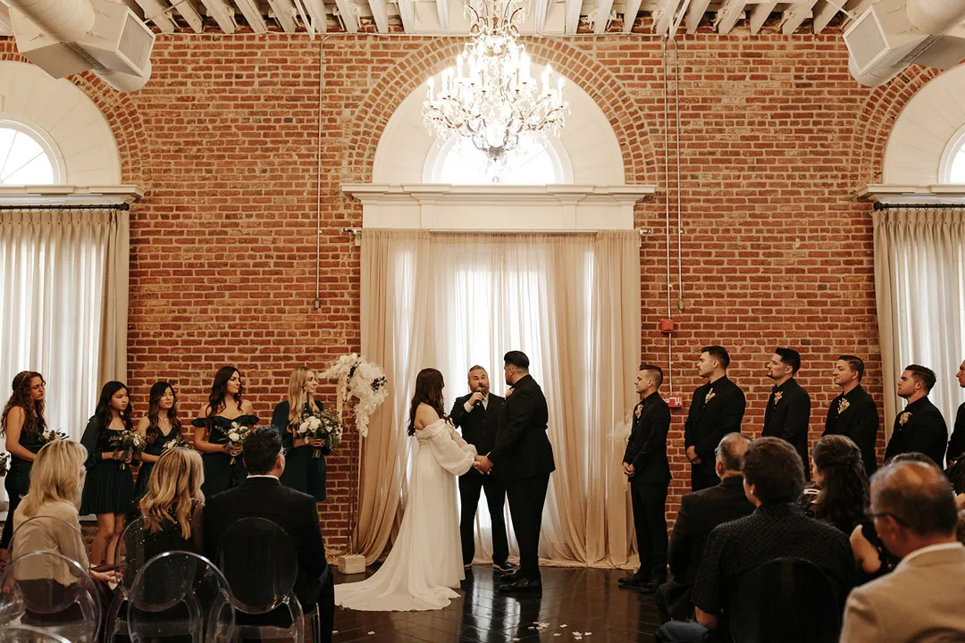 Wedding guests face the couple at their ceremony.