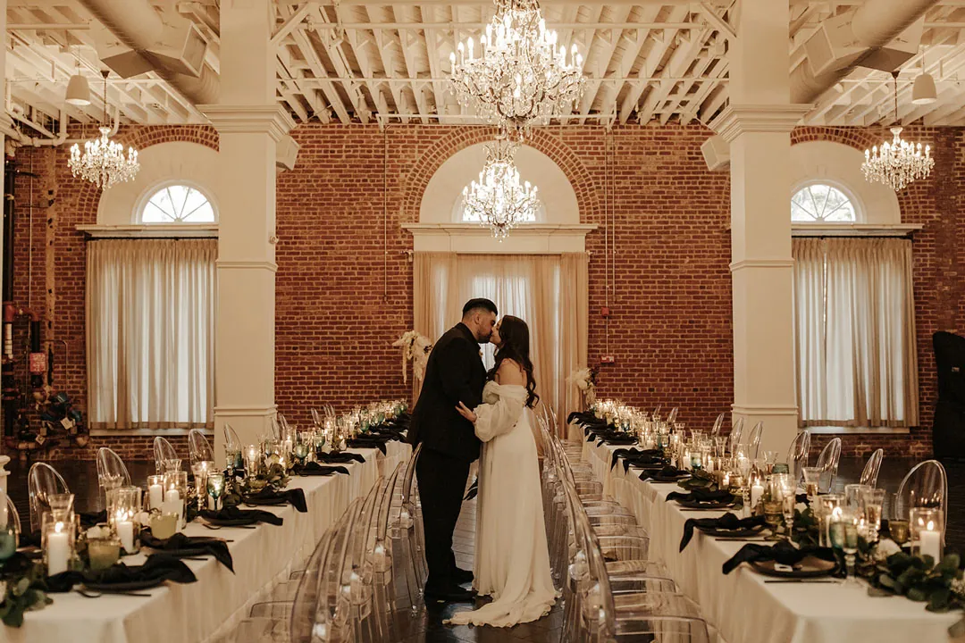 Couple embrace between long reception tables.