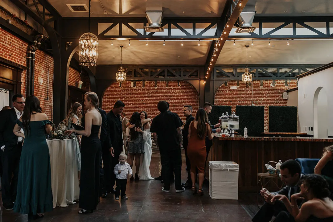 Guests mingle around outdoor cocktail tables.