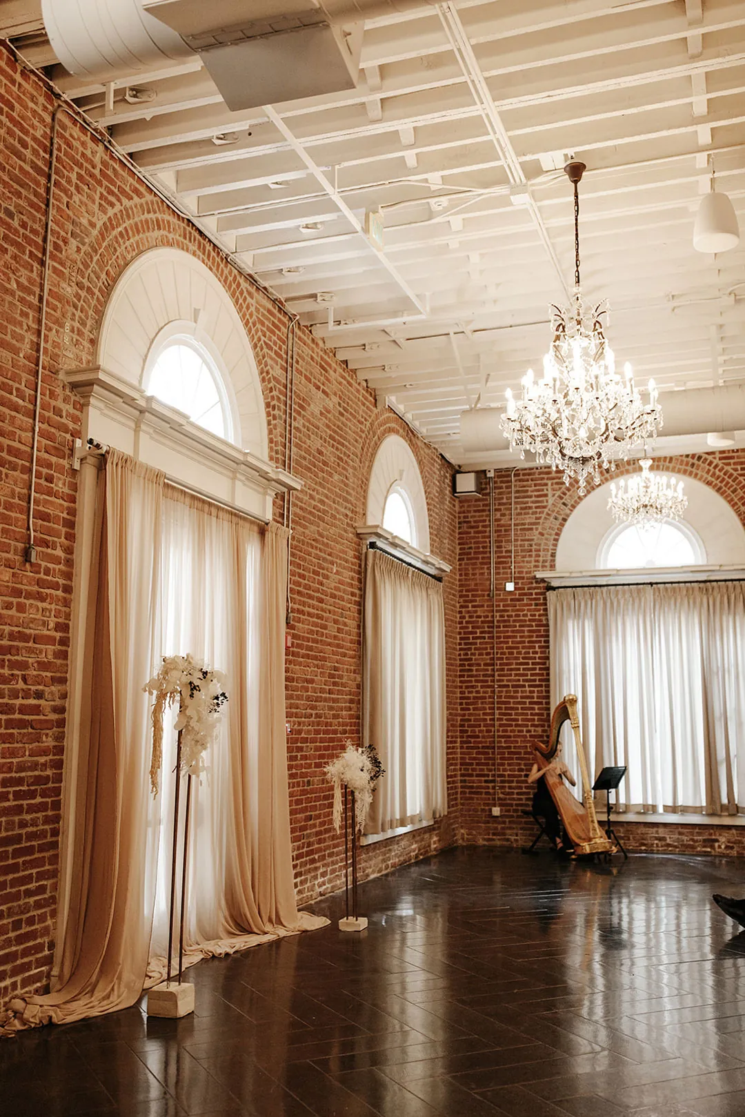 Empty ballroom beneath chandeliers and white ceiling beams.