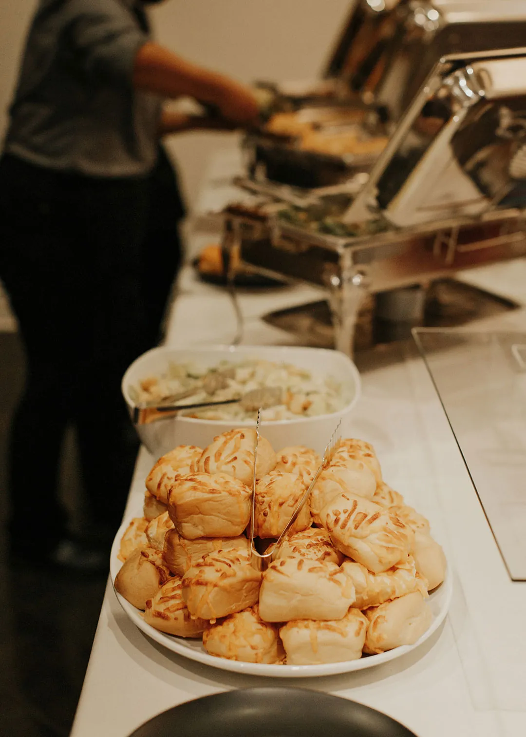 Rolls and warm food at a reception buffet.