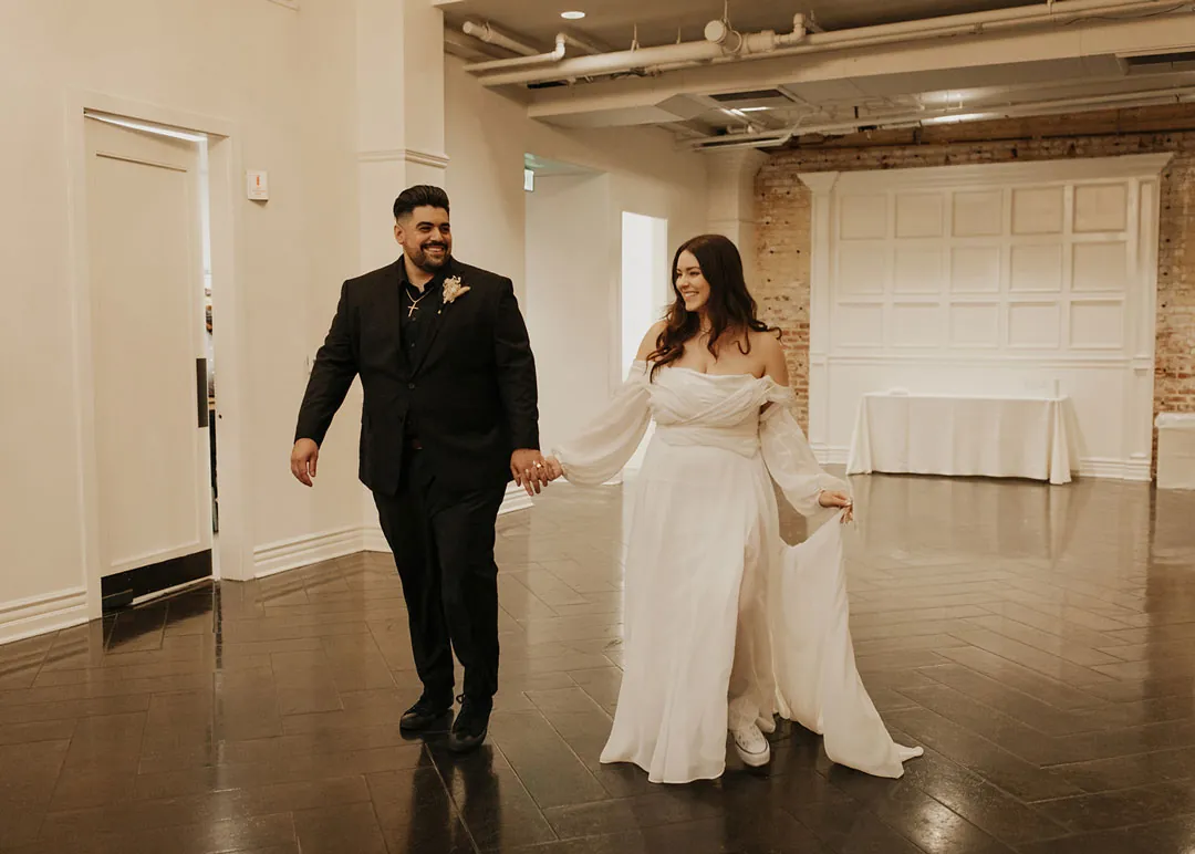 Newlyweds enter the reception holding hands.