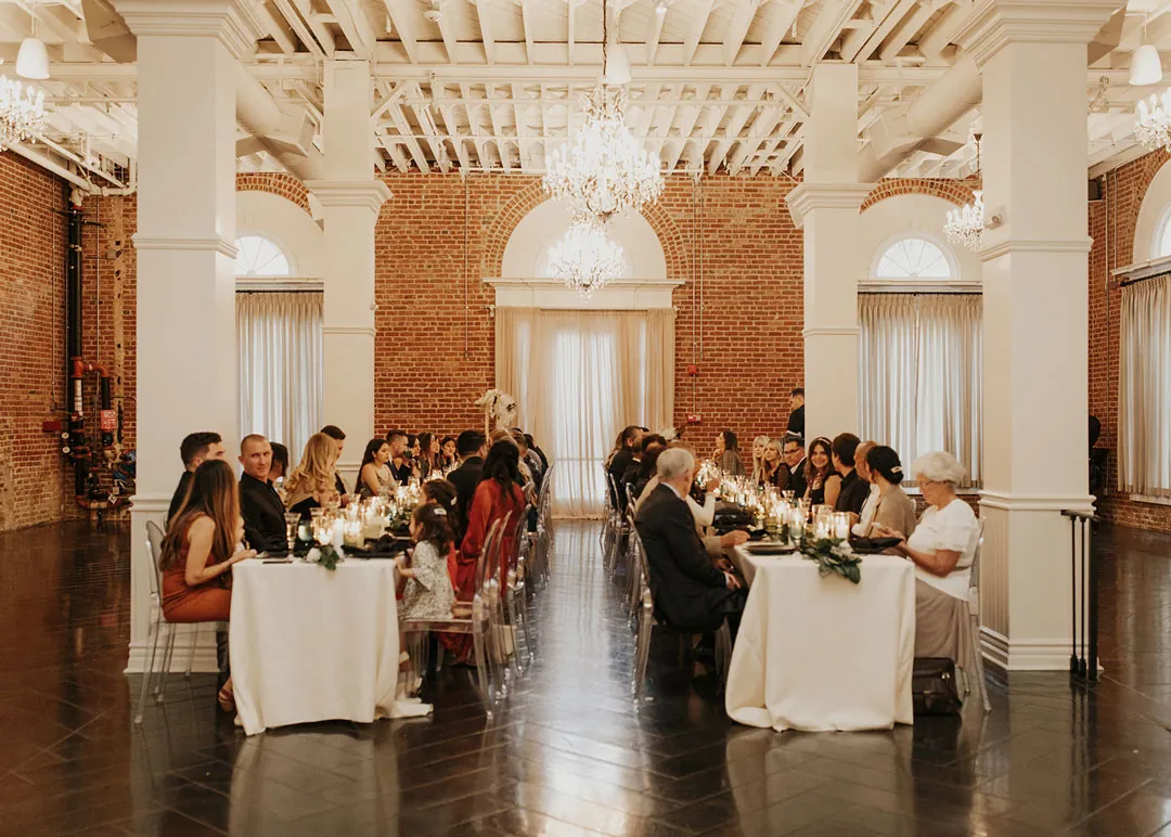 Guests dine at tables along the ballroom aisle.