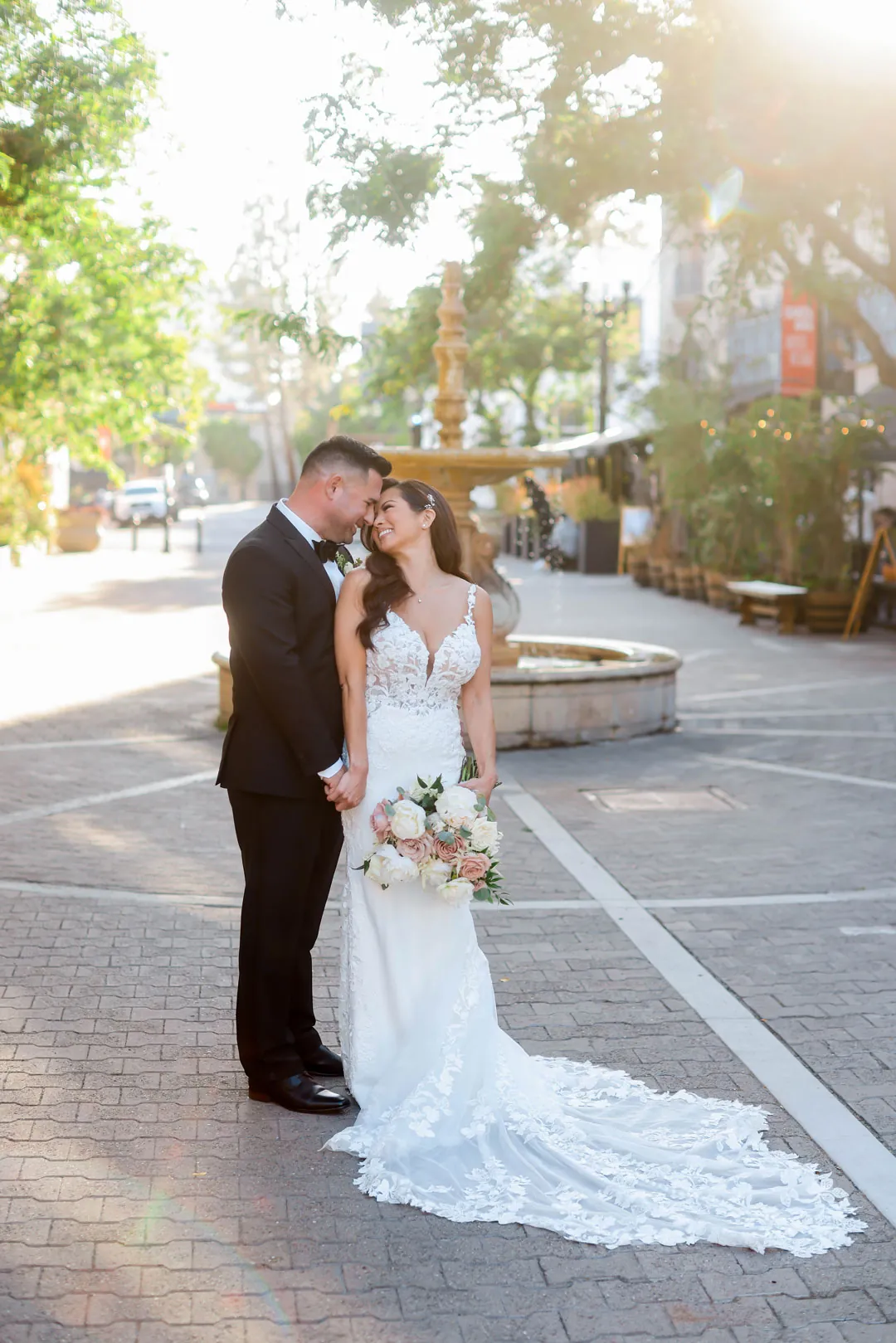 Newlyweds embracing beside an outdoor fountain