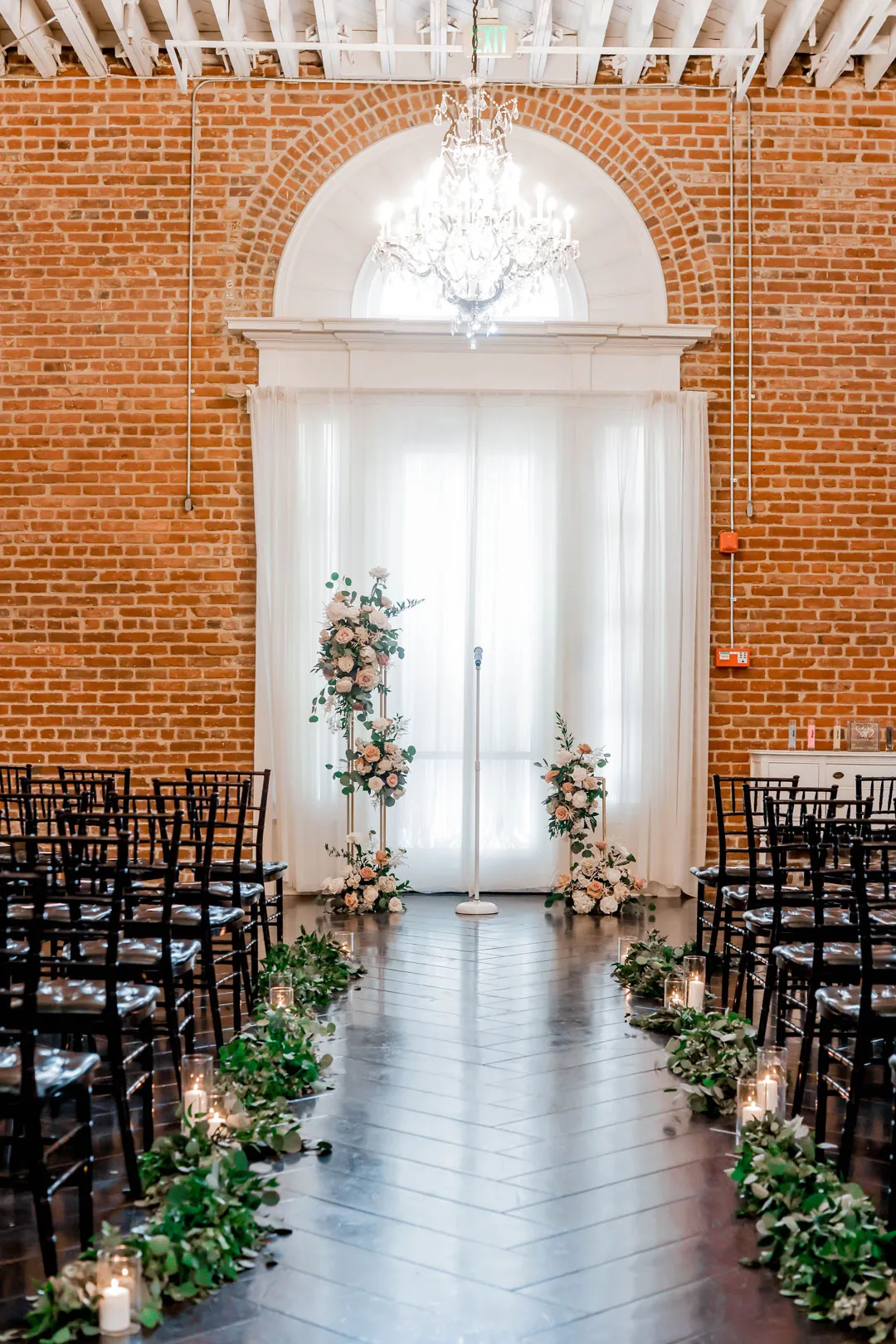 Ceremony aisle lined with flowers beneath a chandelier