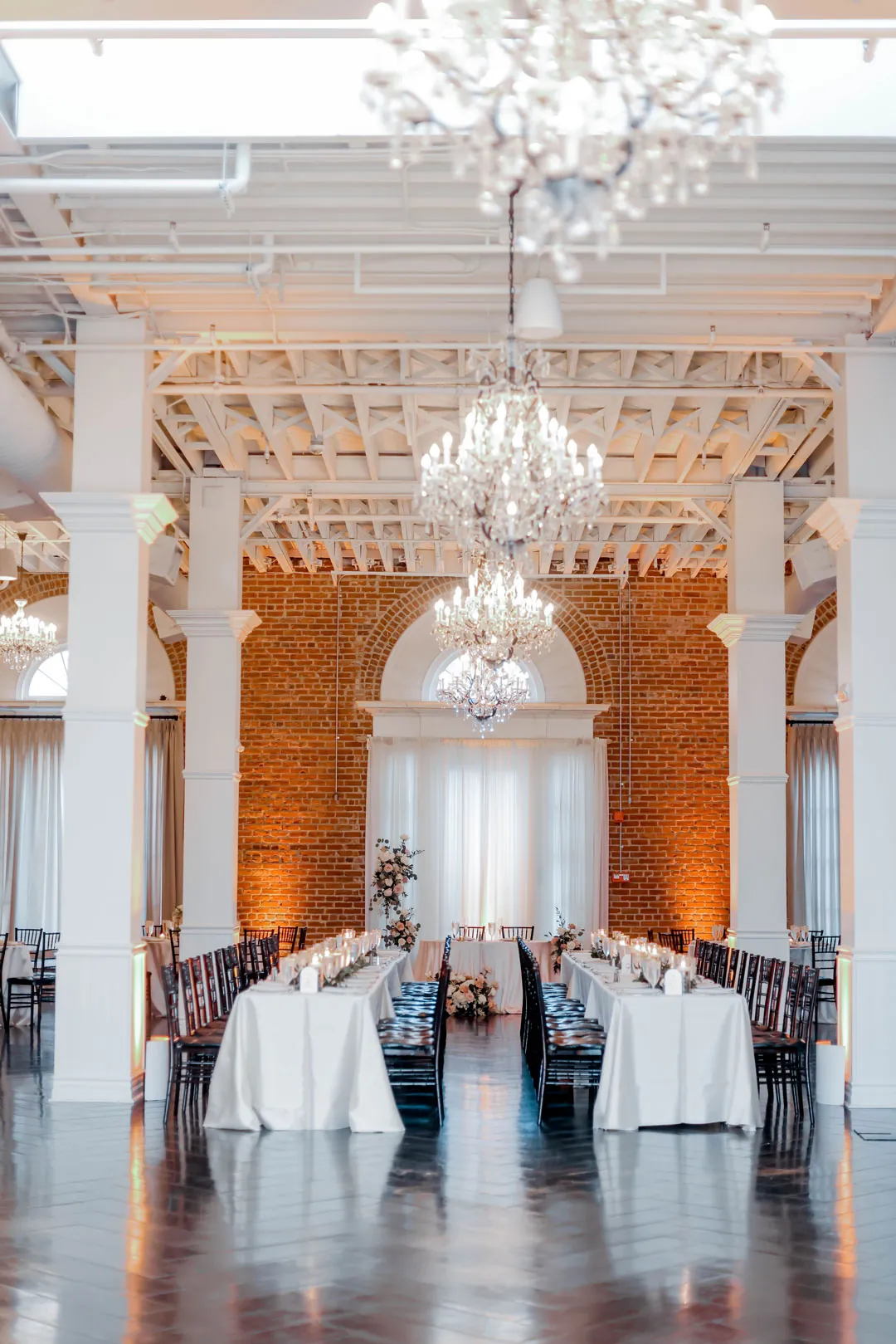 Reception tables beneath white beams and chandeliers