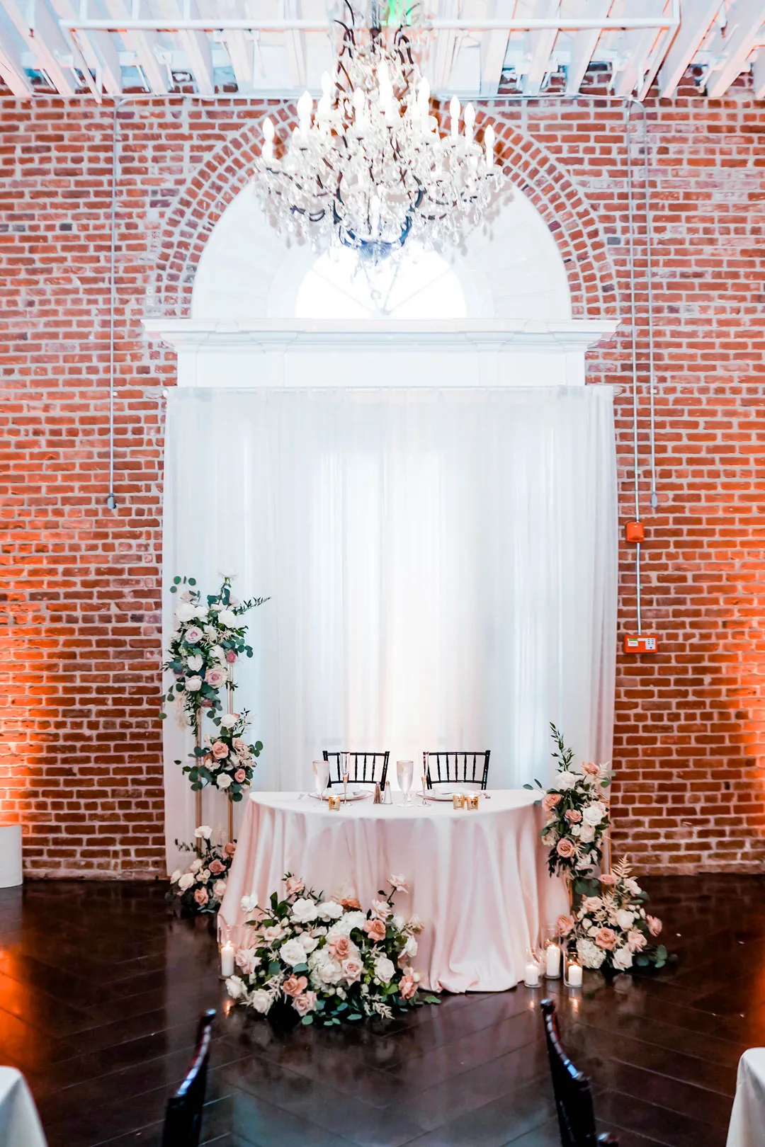 Sweetheart table beneath a ballroom chandelier