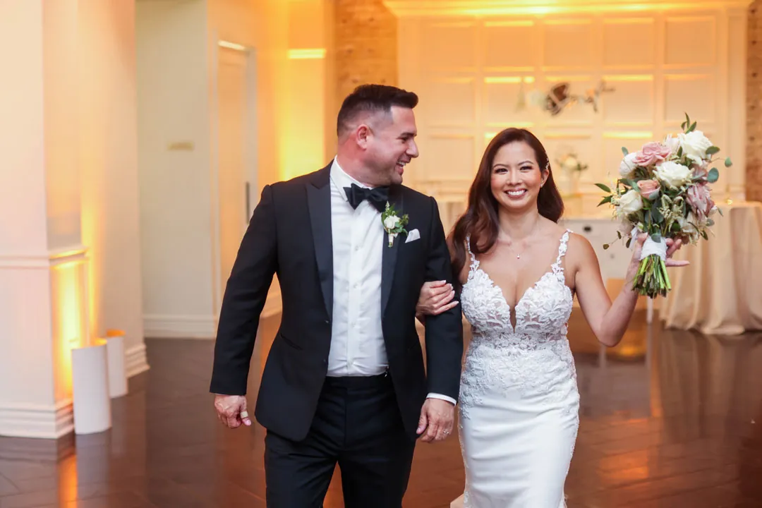 Newlyweds smiling while entering their reception