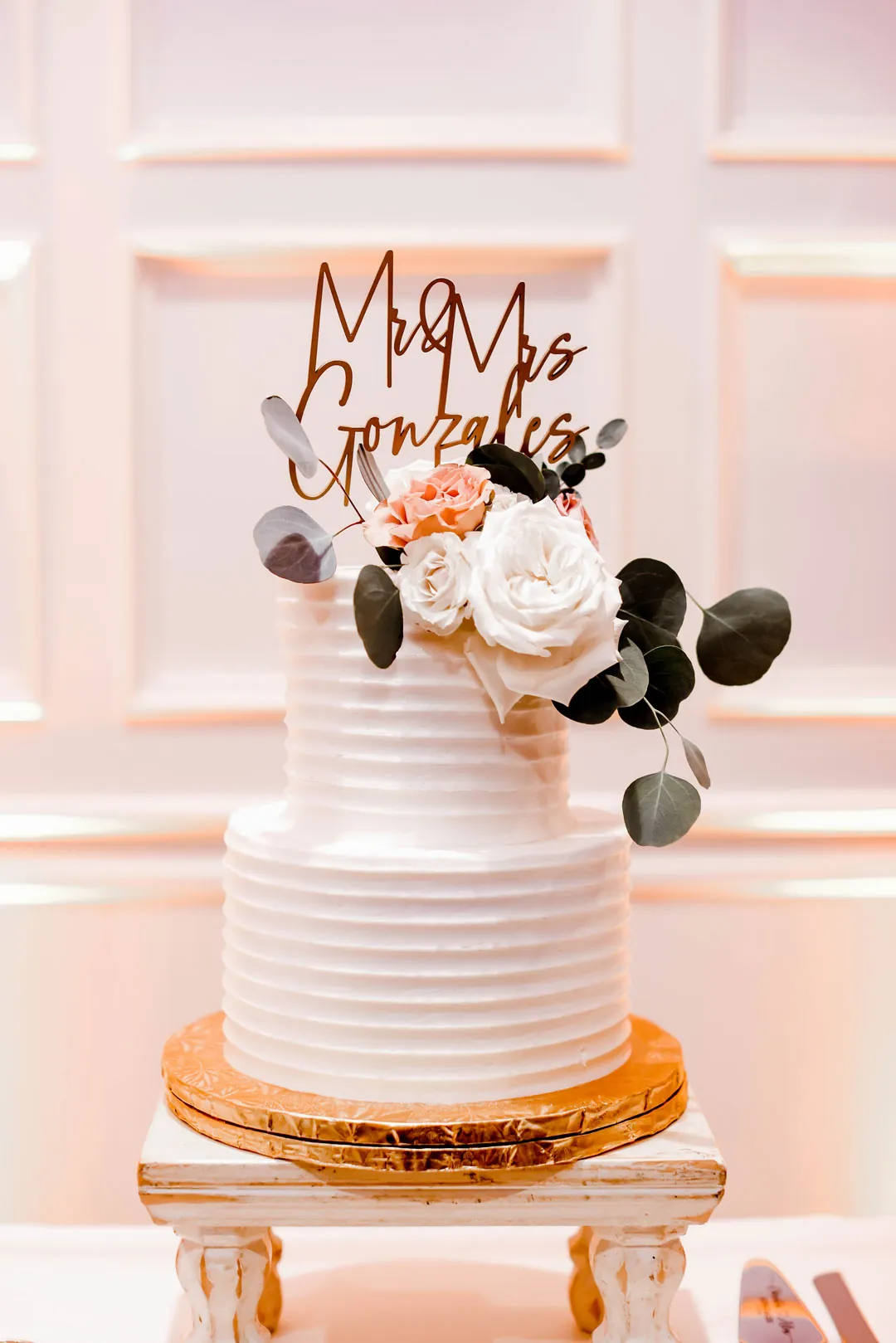 White tiered cake decorated with pale flowers