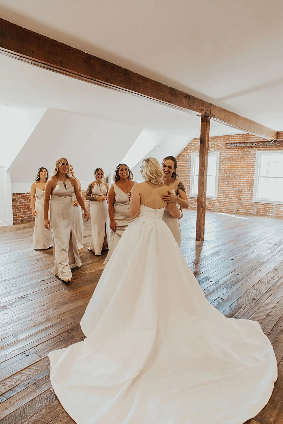 Bride approaching her bridesmaids in a bright room