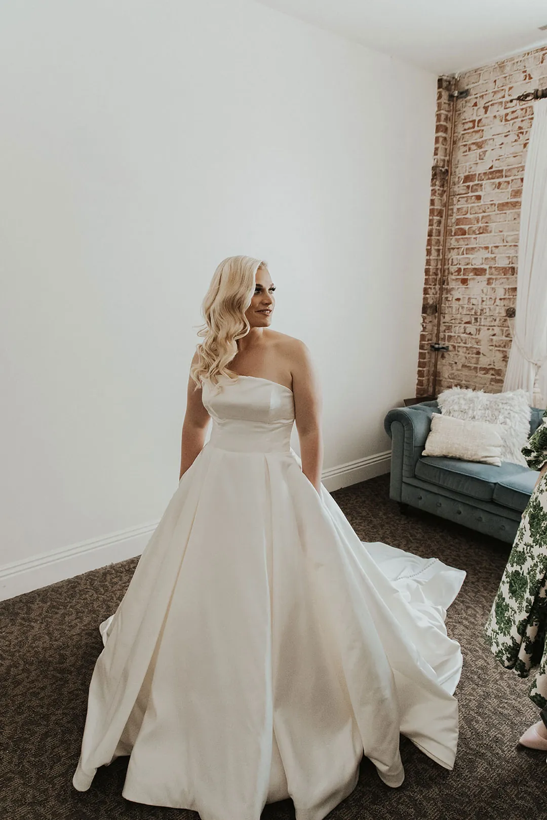 Bride standing in a lounge with her skirt spread behind her
