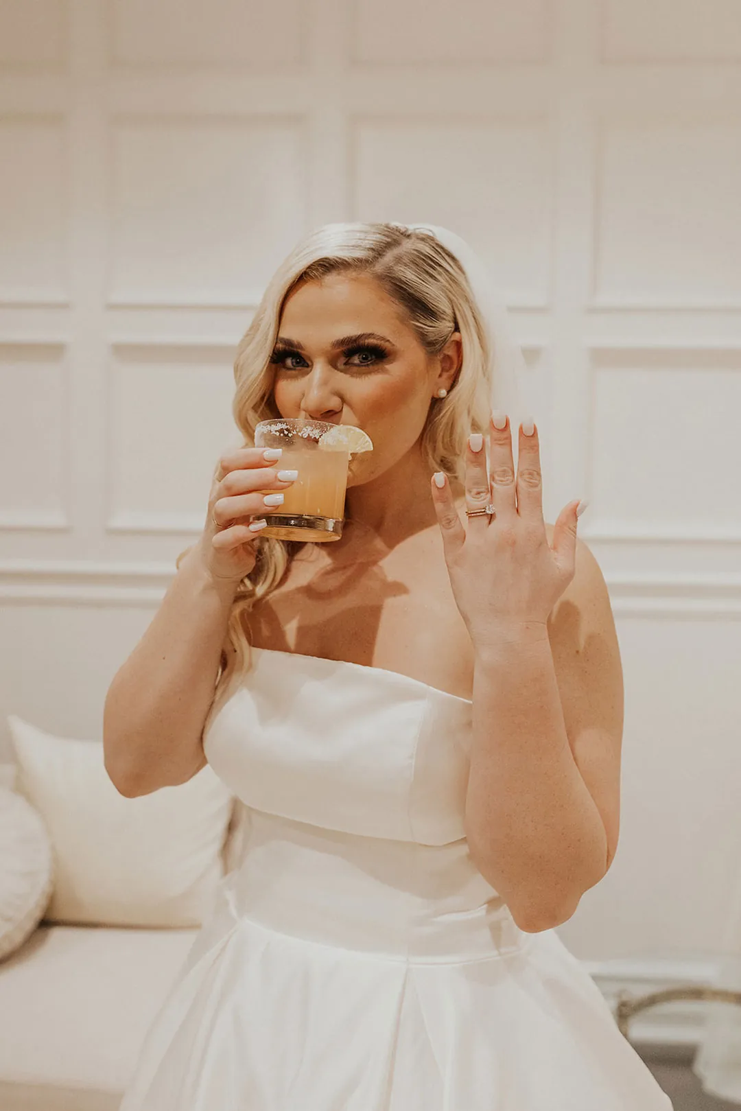 Bride raising a small glass while smiling at the camera