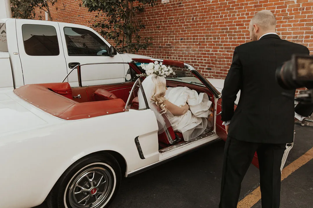 Couple standing beside a white convertible with red seats