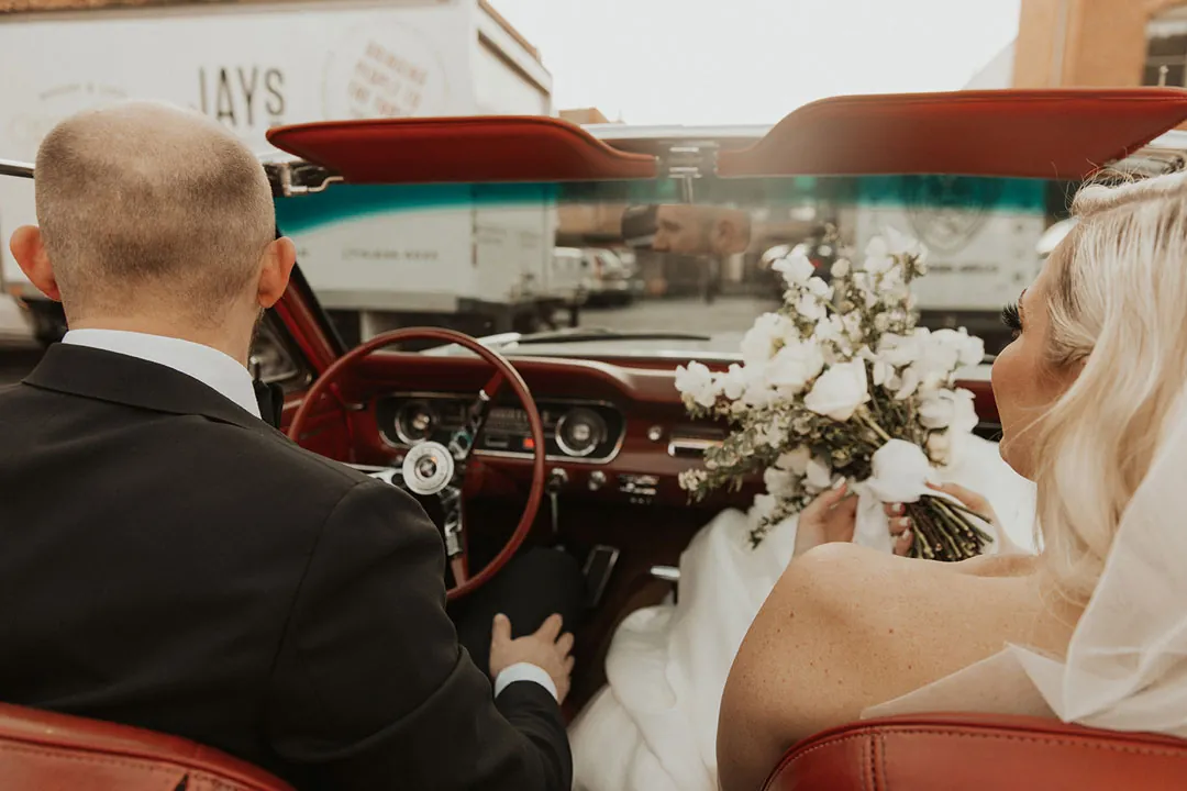View from behind the couple seated in a white convertible