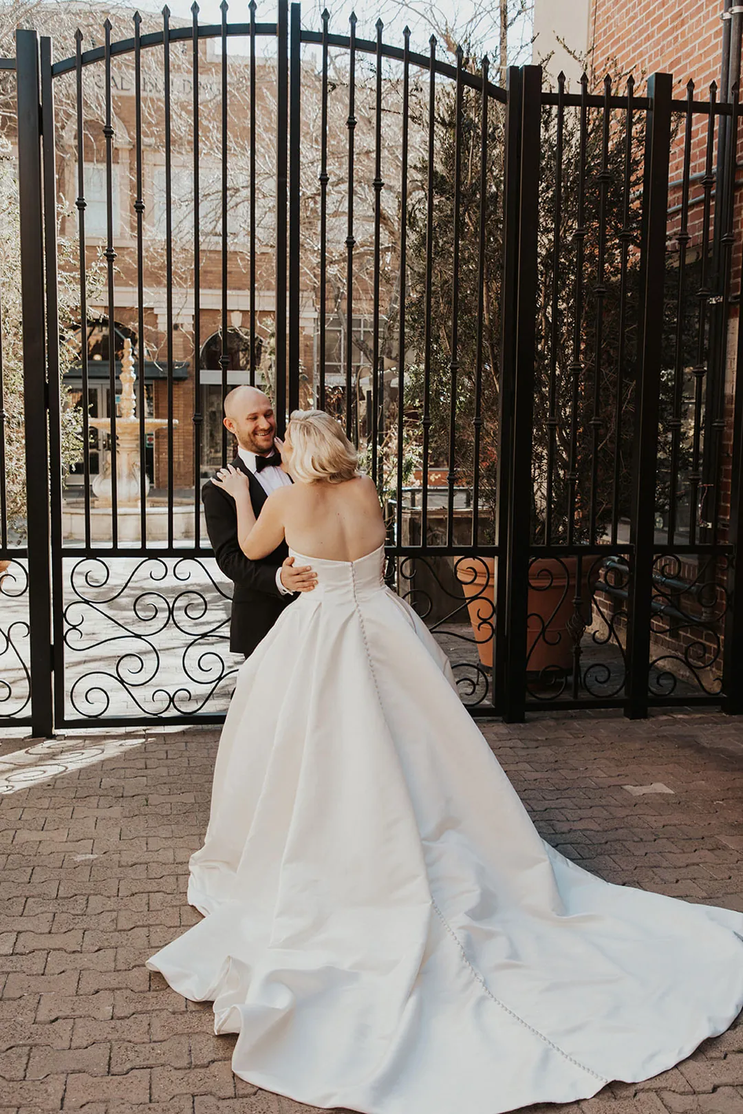 Couple embracing before a tall iron gate