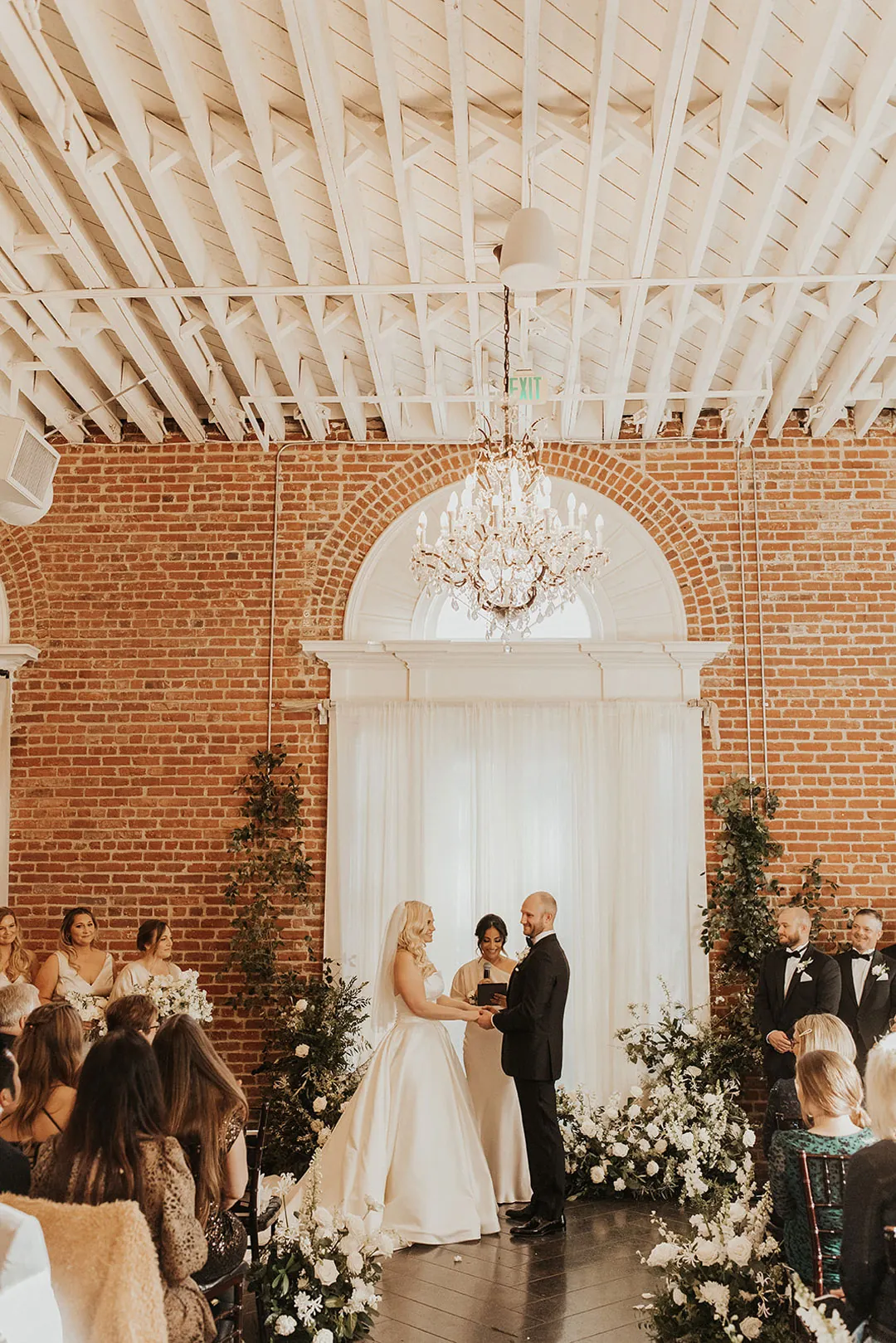 Couple standing before a floral ceremony backdrop