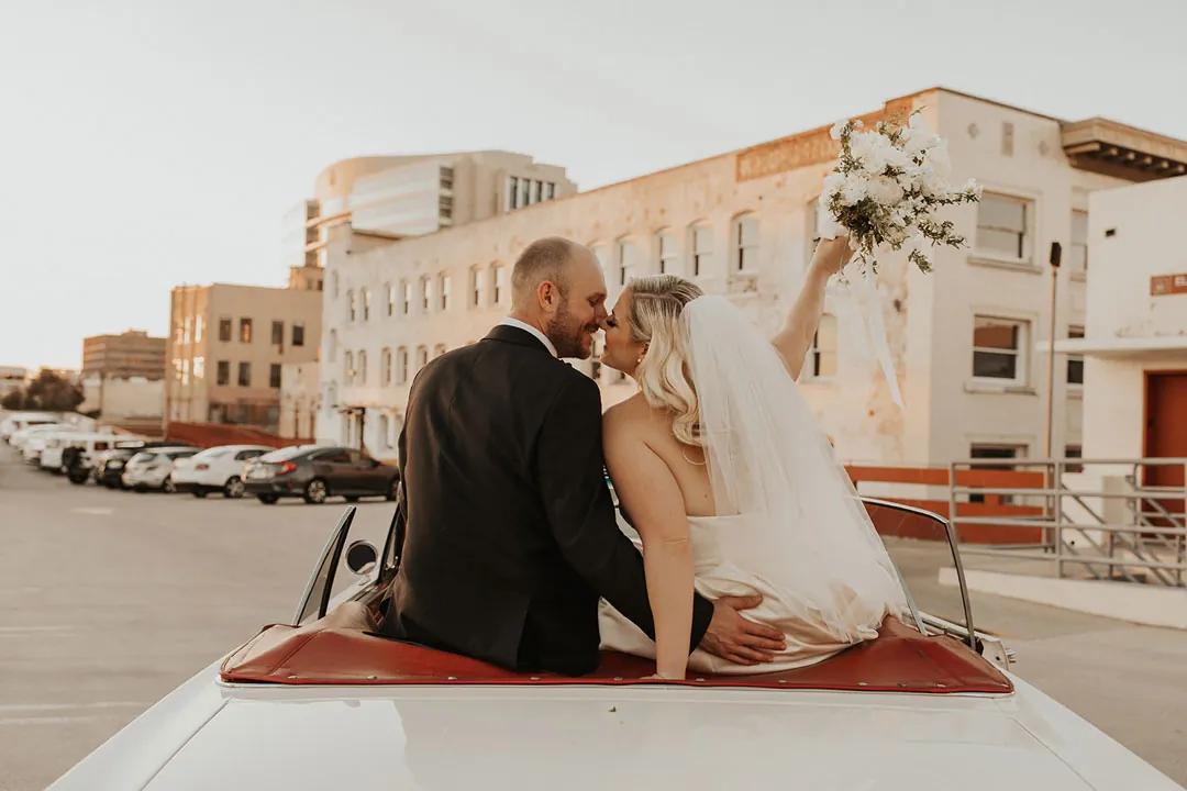 Couple seated together above the rear seat of a convertible