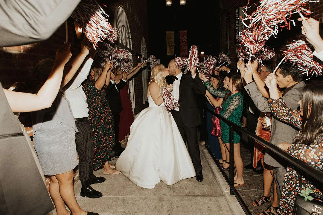 Couple walking beneath guests' raised metallic streamers