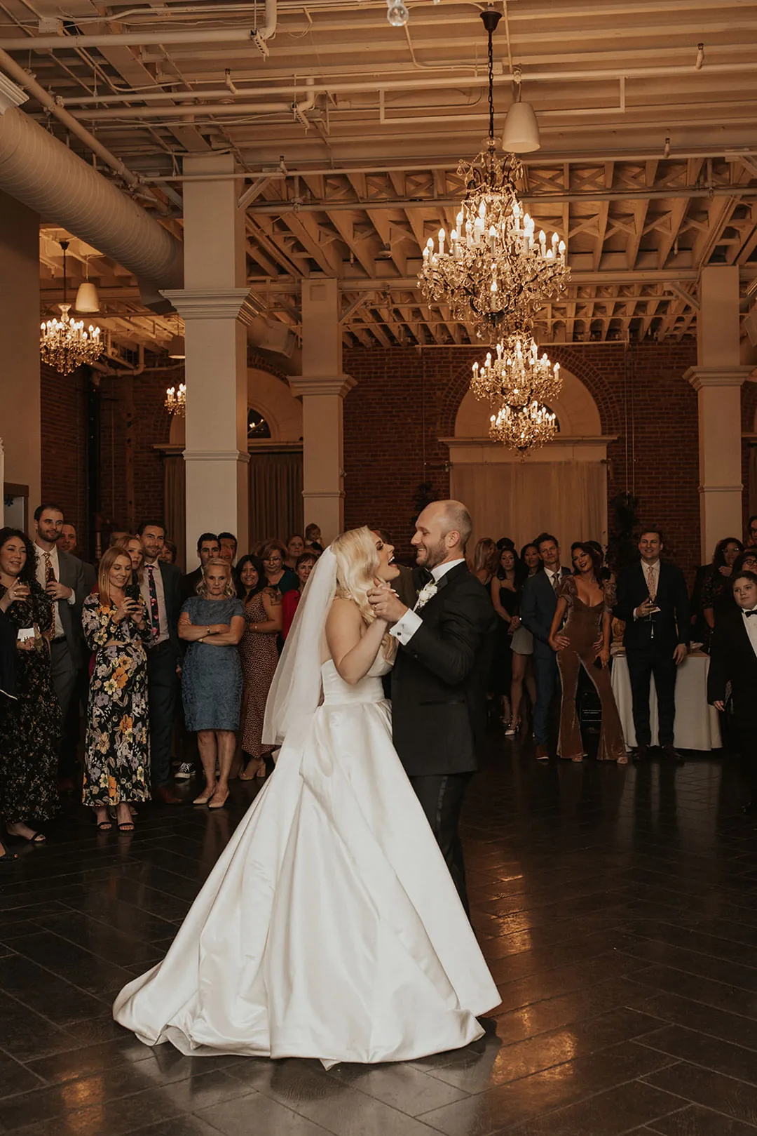 Couple dancing beneath chandeliers in the reception room