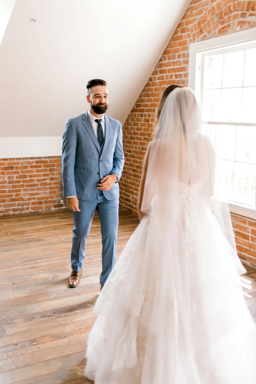 Groom facing the bride beneath a sloped ceiling