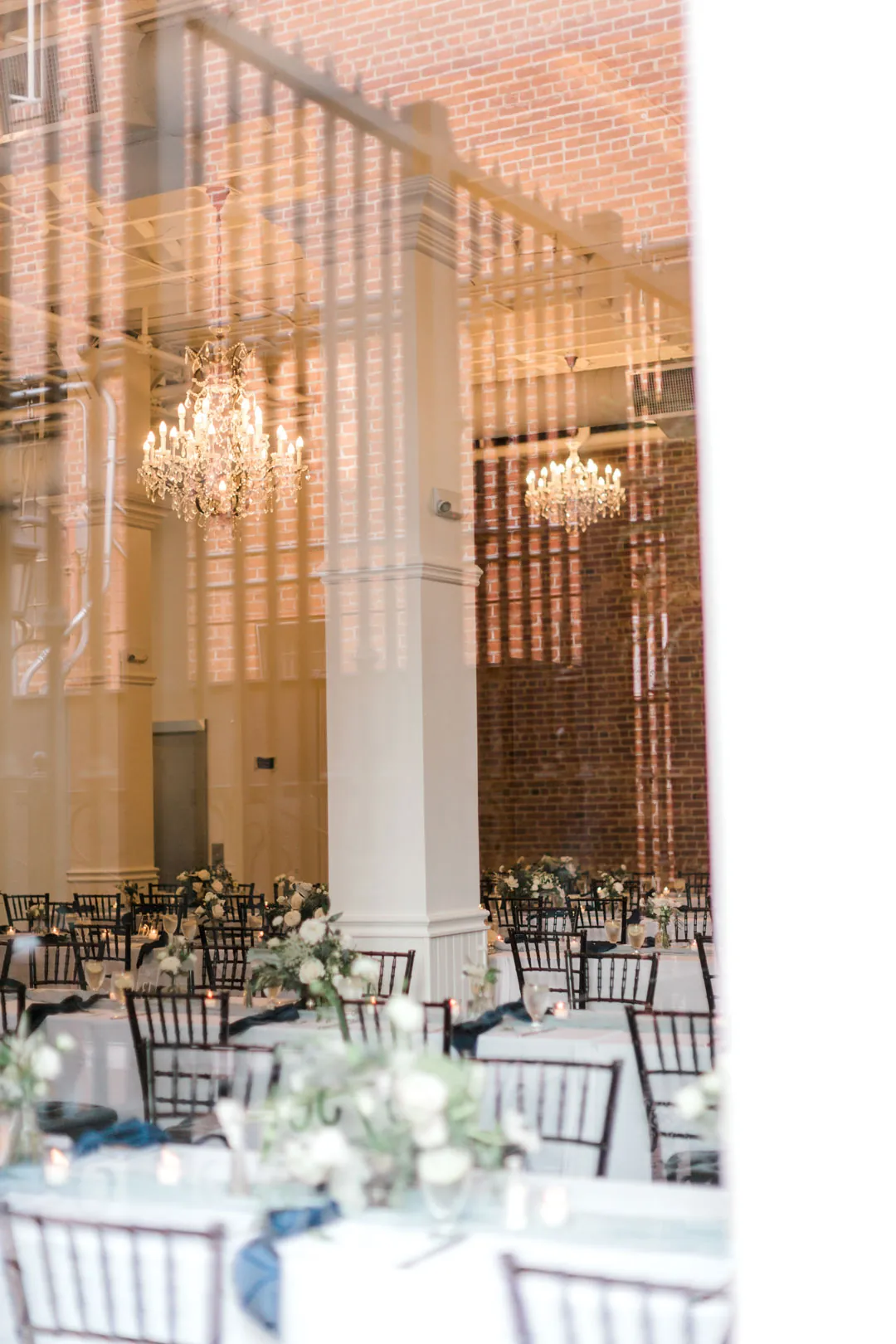 Reception tables beneath chandeliers and exposed ceiling beams