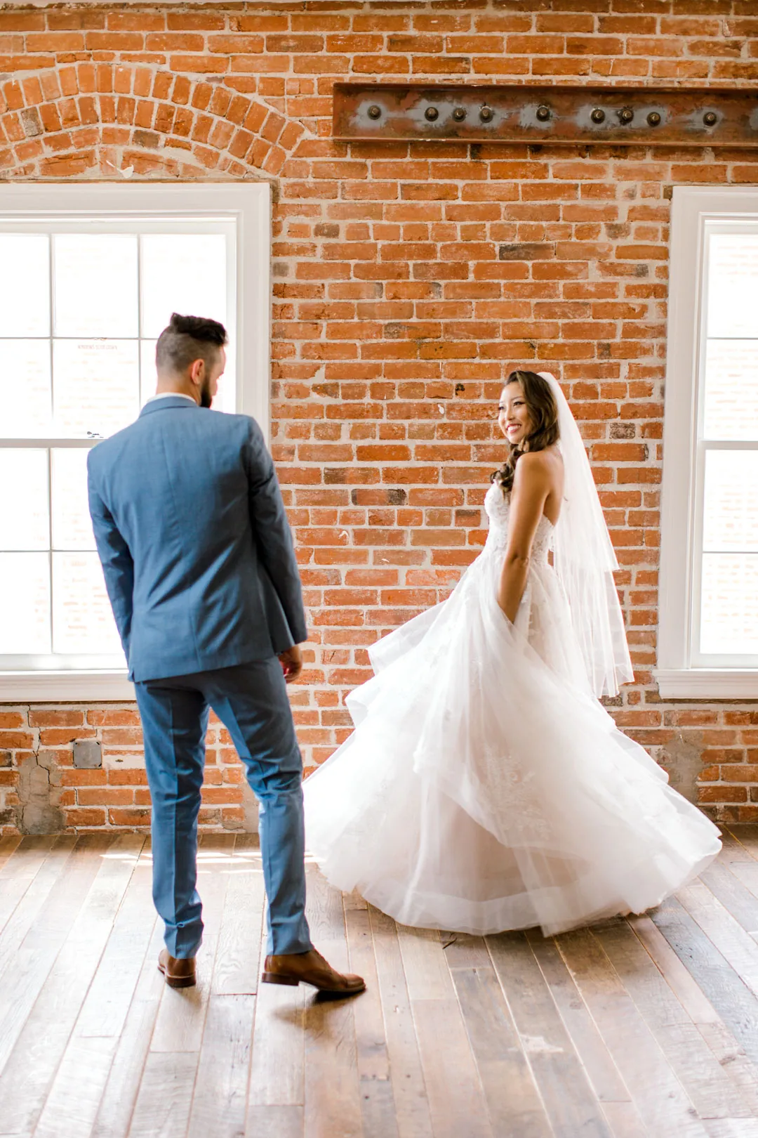 Groom twirling the bride in a bright room