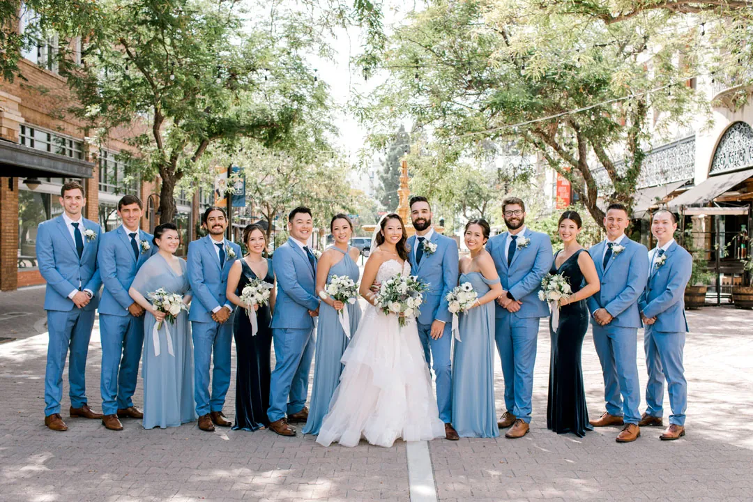 Wedding party posing together on a tree-lined city sidewalk