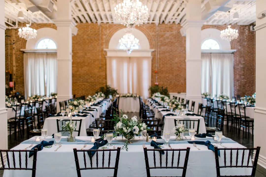 Round reception tables set with white linens and greenery