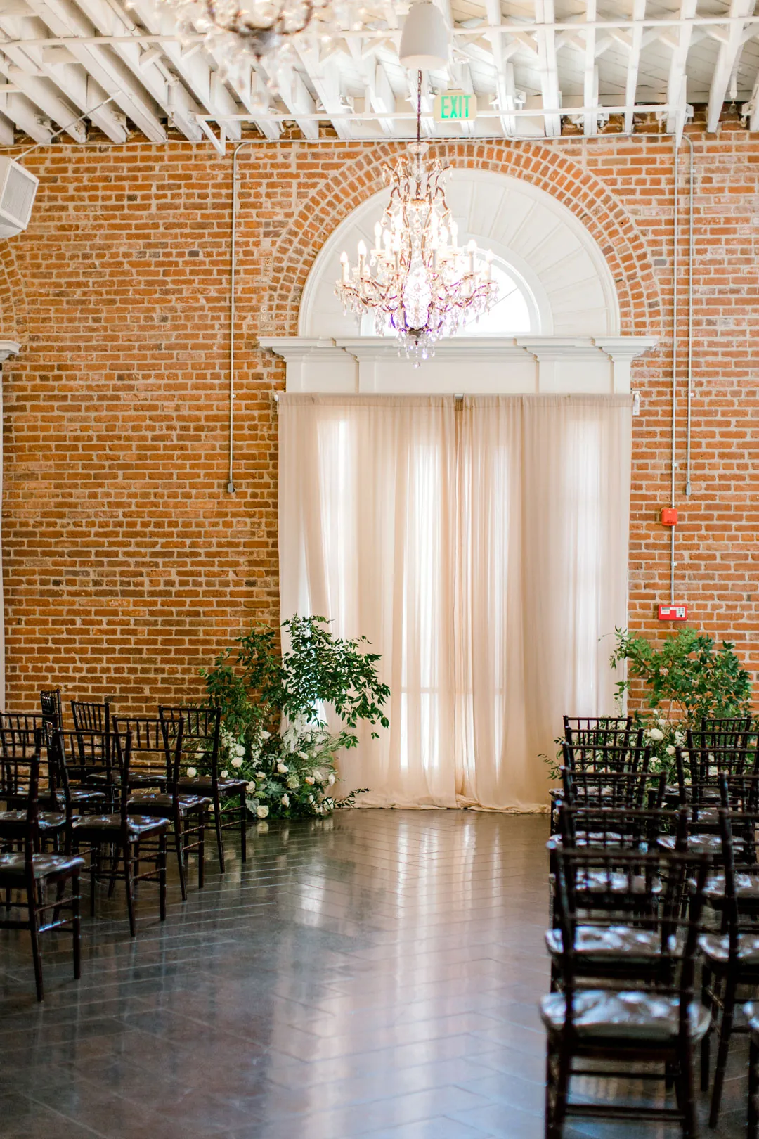 Ceremony aisle beneath an arched window and chandelier