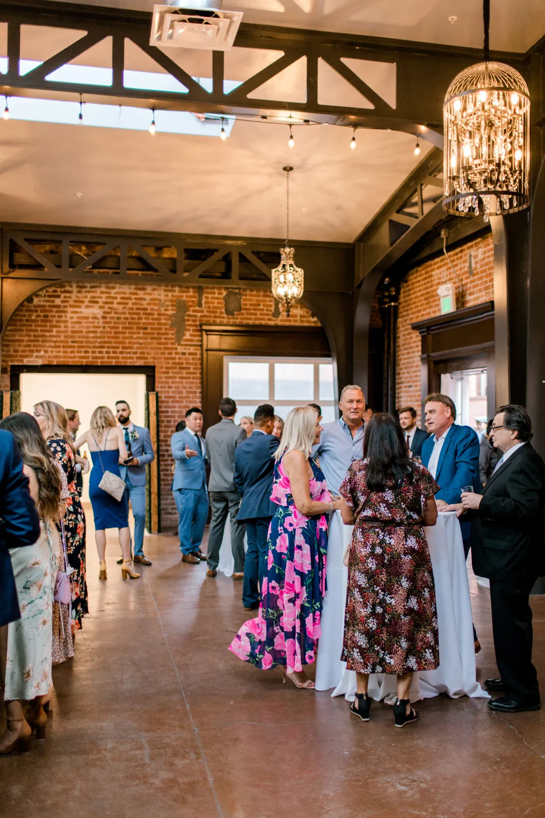 Guests mingling beneath chandeliers in a cocktail reception room