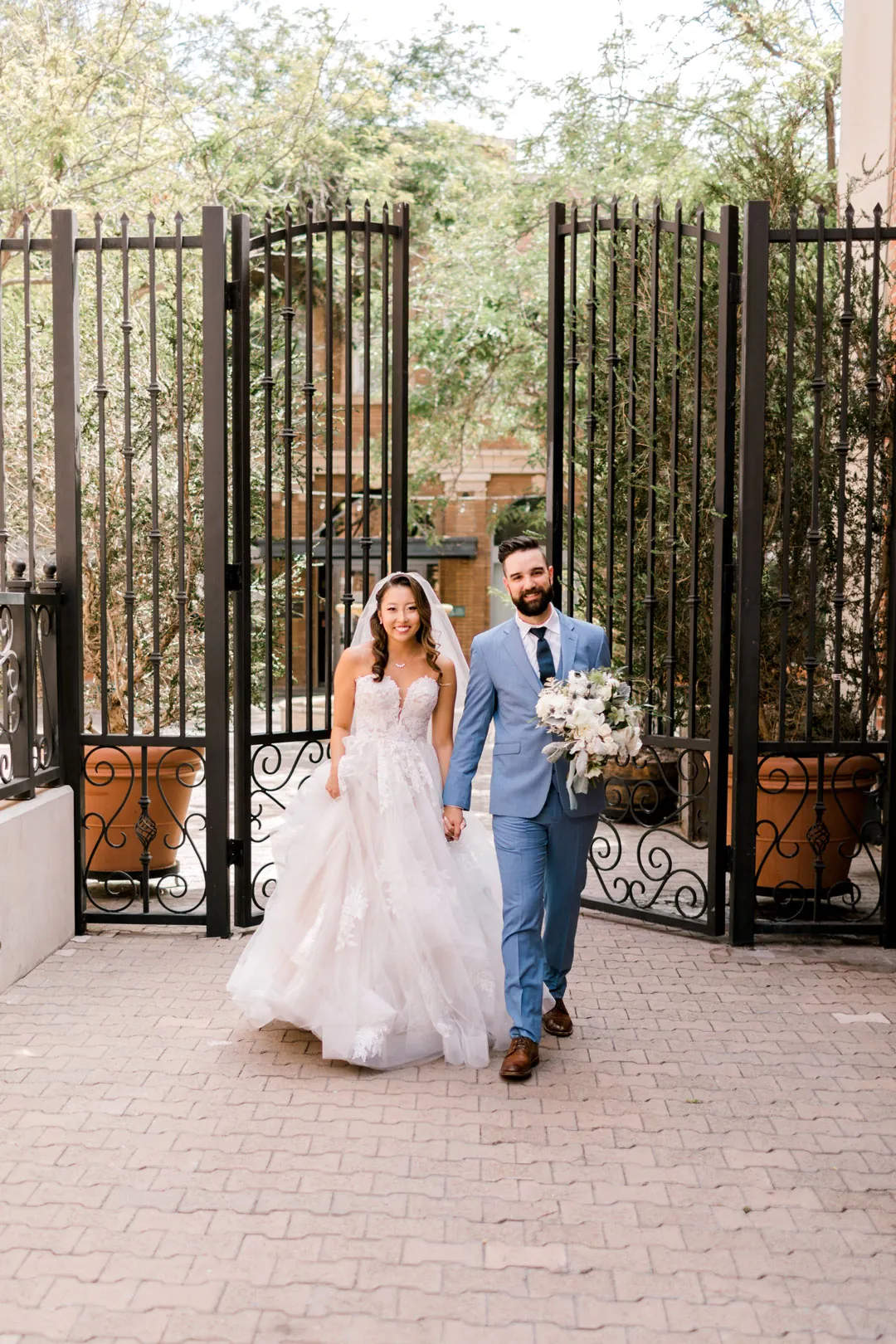 Couple walking hand in hand through an iron gate