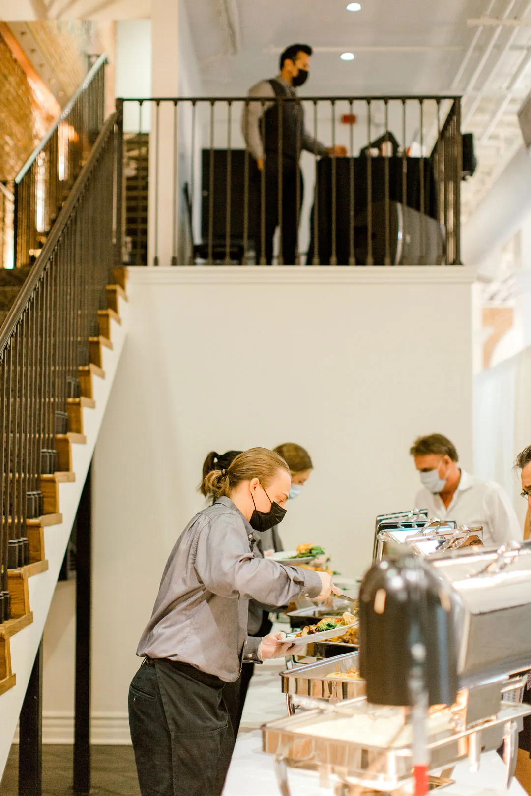 Servers helping guests at a buffet beside a staircase