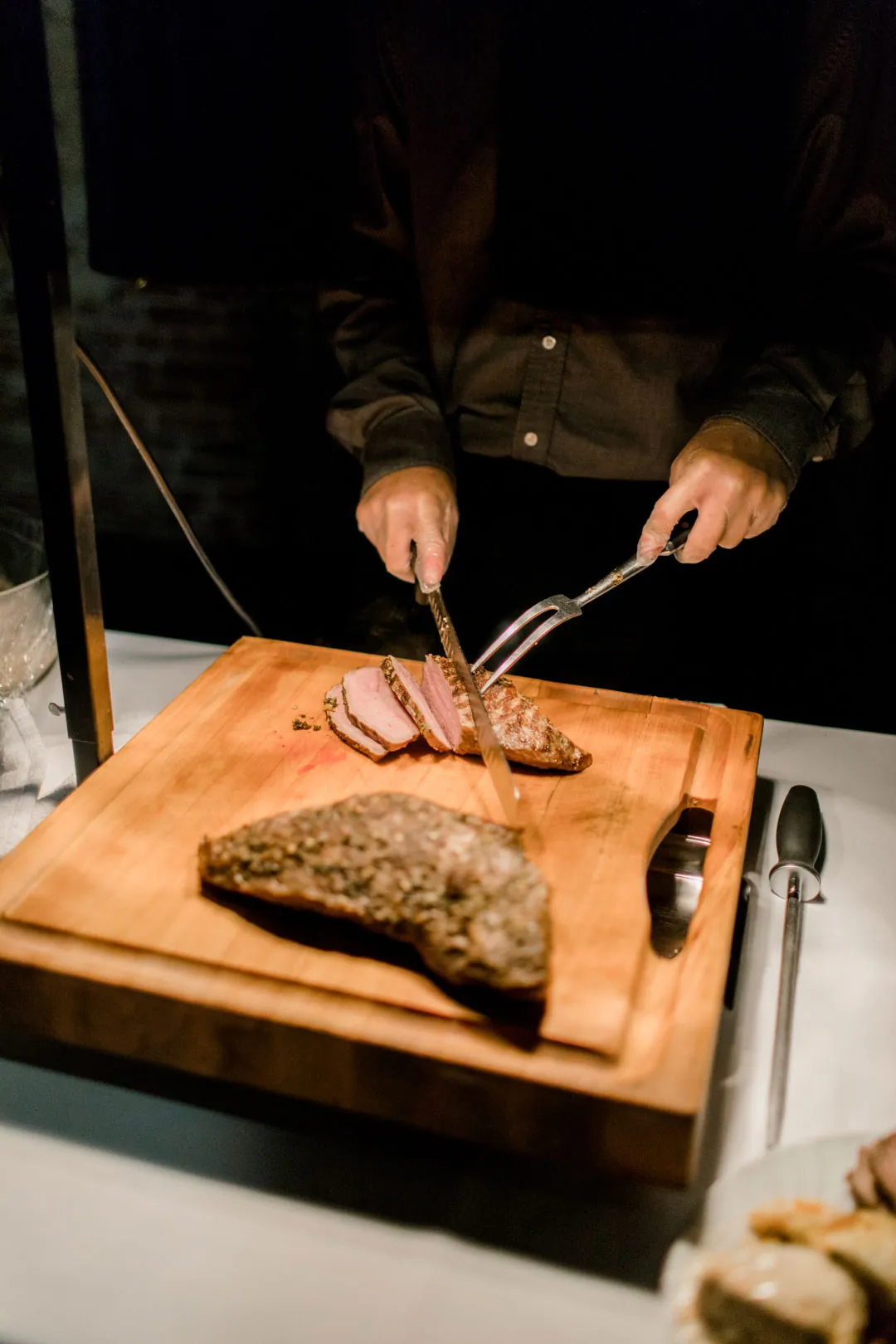 Hands carving meat on a wooden board