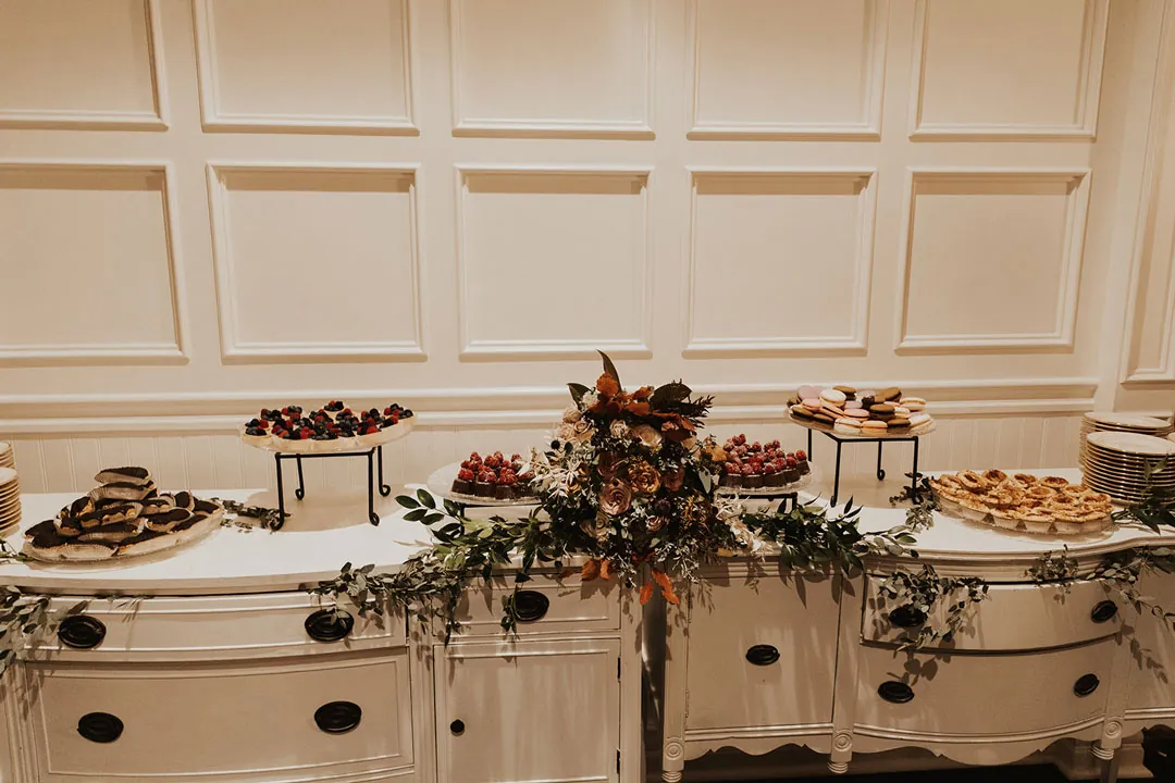 Dessert buffet with flowers on a white cabinet