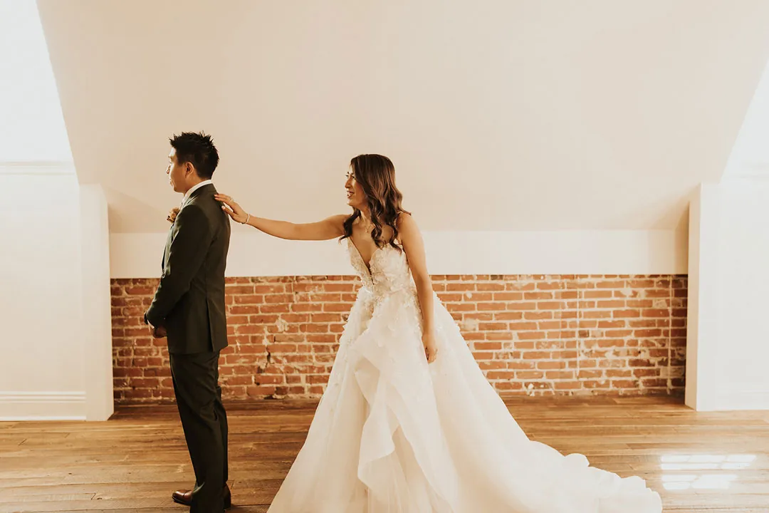 Bride reaching toward the groom during their first look